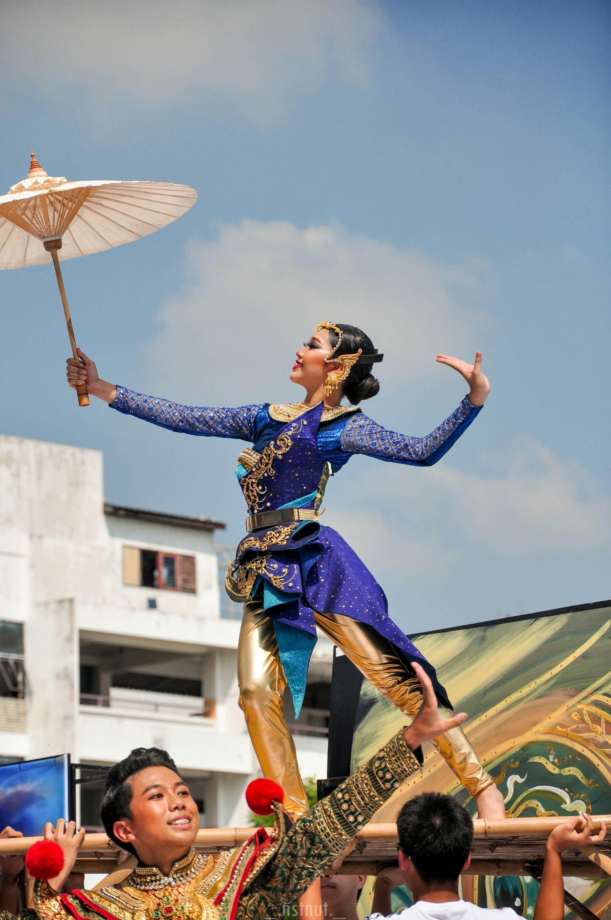 a woman in a blue and gold costume holding an umbrella