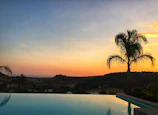 Infinity pool shimmering under a golden sunset beside a modern villa.
