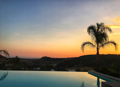 Infinity pool shimmering under a golden sunset beside a modern villa.