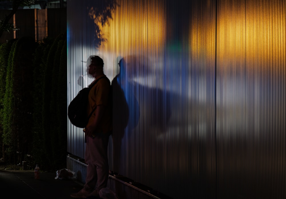 a man standing next to a wall with a painting on it