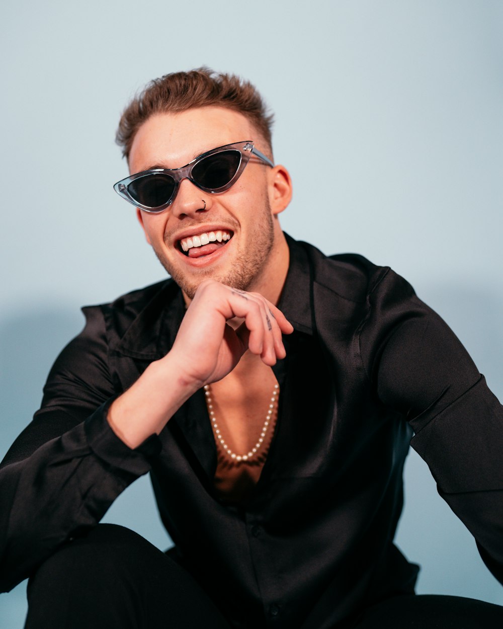 a man in a black shirt and sunglasses posing for a picture