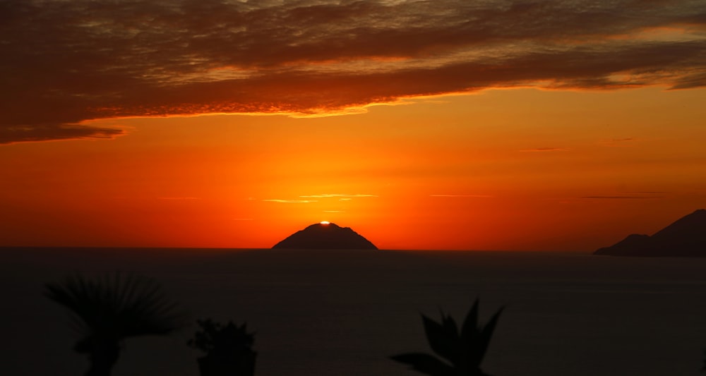 the sun is setting over a small island