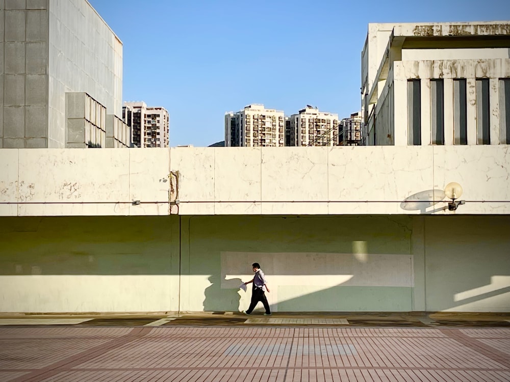 a man walking down a street next to tall buildings