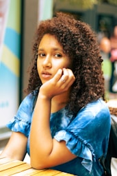 a woman sitting at a table with a cell phone to her ear