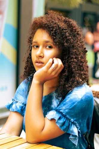 a woman sitting at a table with a cell phone to her ear
