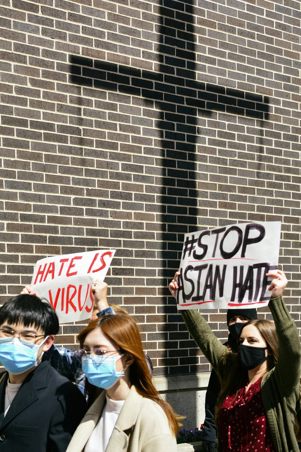 a group of people holding up signs in front of a cross