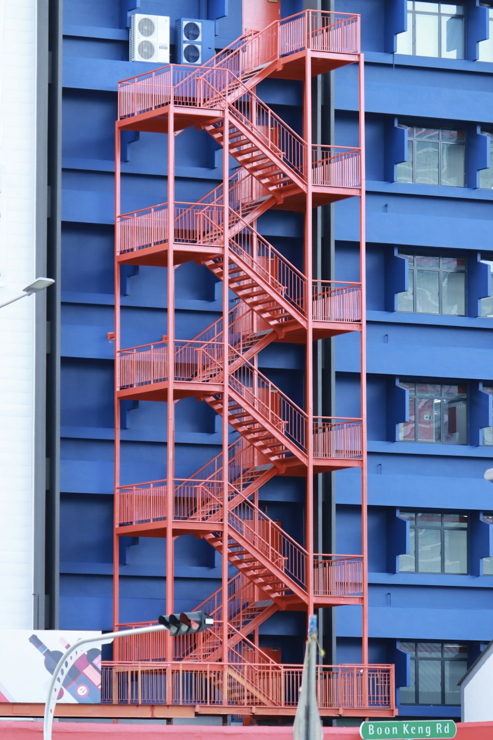 a red fire escape next to a tall blue building