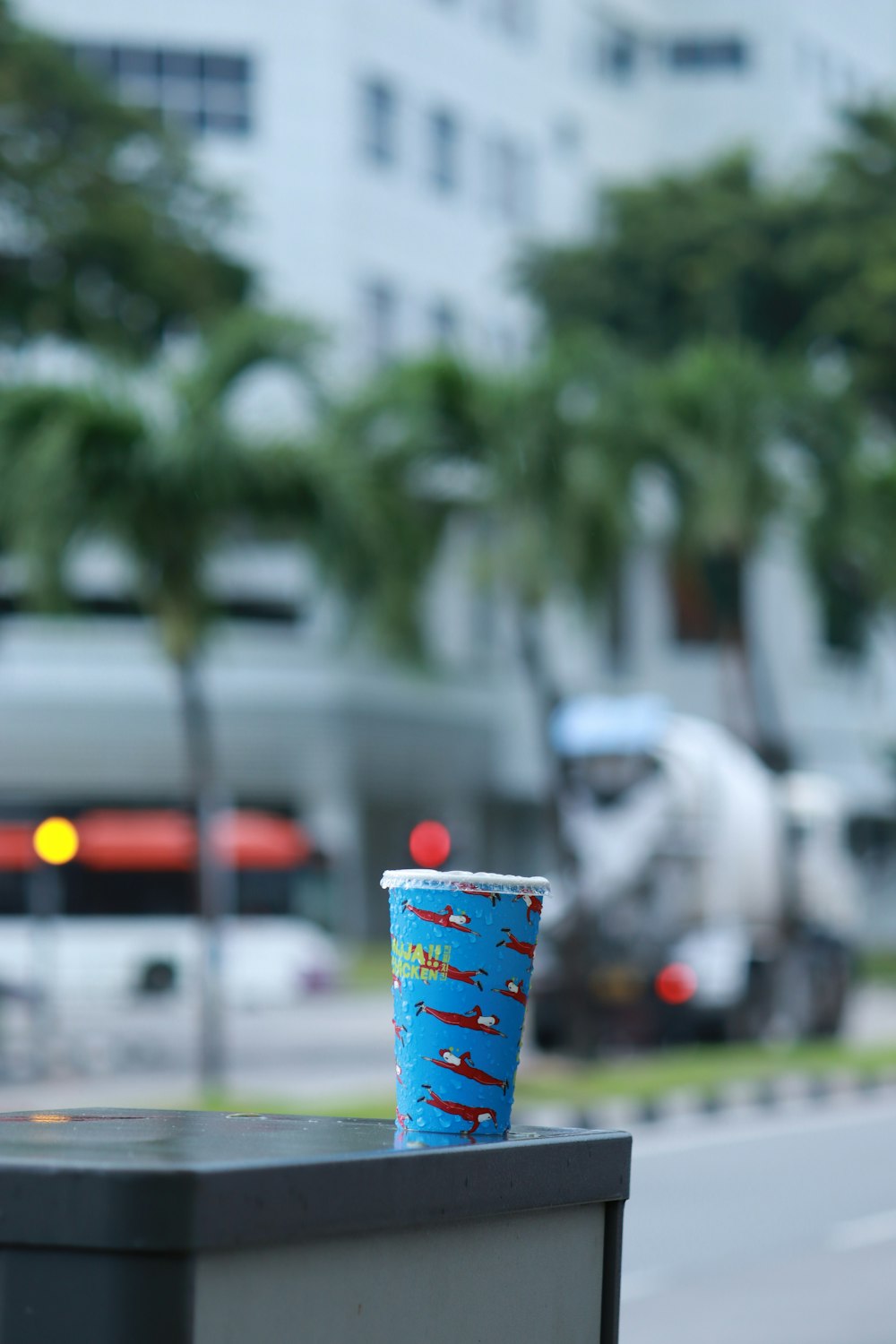 a blue cup sitting on top of a trash can