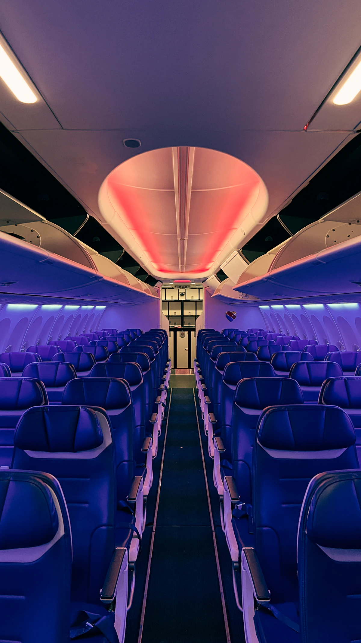 Interior of an airliner cabin looking down the aisle between seat rows