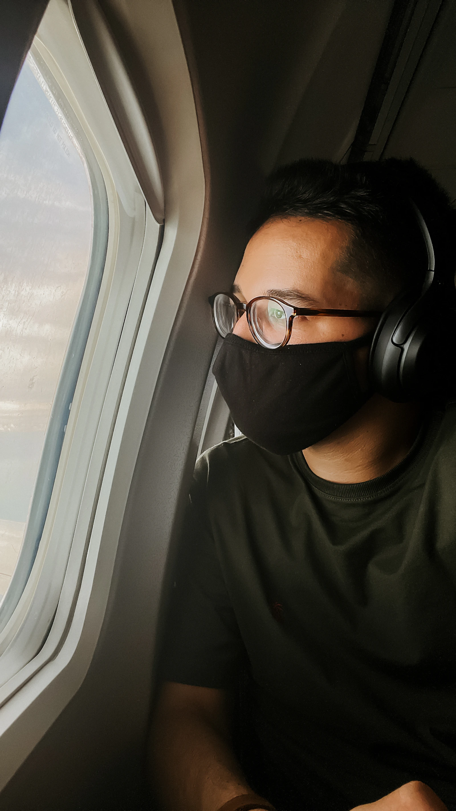 Pasajera con los auriculares puestos junto a la ventanilla del avión