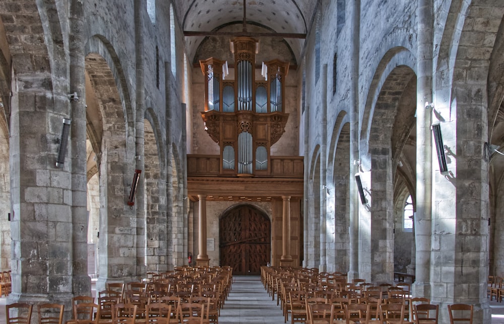 a church with rows of wooden chairs and a pipe organ