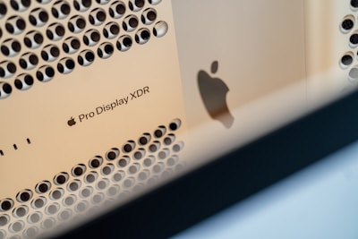 A close-up view of an Apple Pro Display XDR showing its distinctive perforated design. The image features the Apple logo and the product label clearly. The lighting highlights the metallic texture and sleek finish of the display.