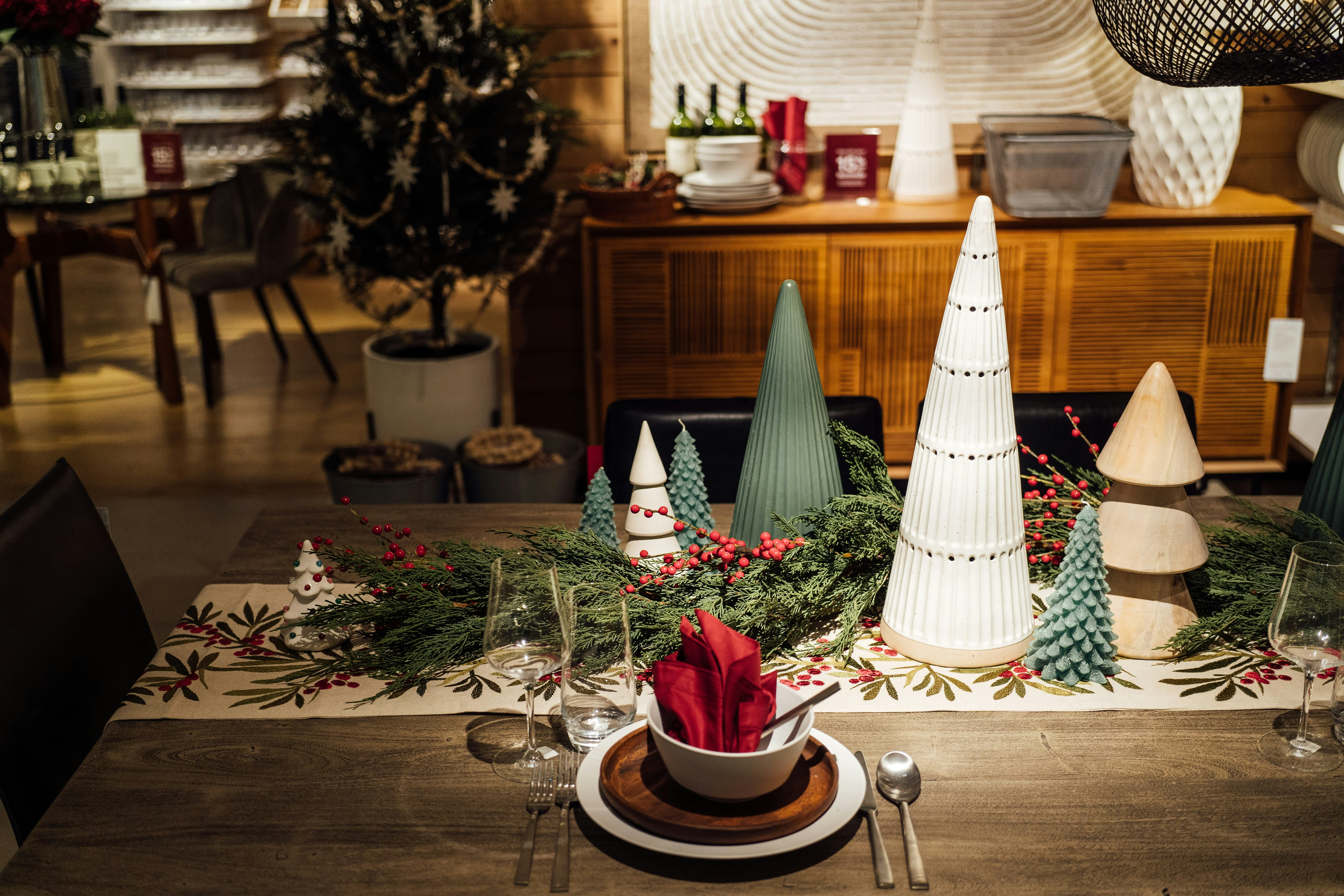 Festive Christmas table setting with evergreen branches and candles.