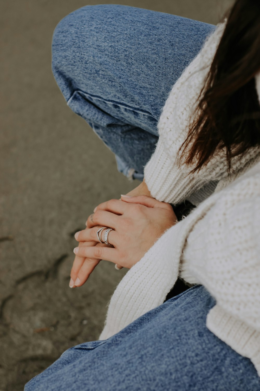 a woman wearing a white sweater and blue jeans