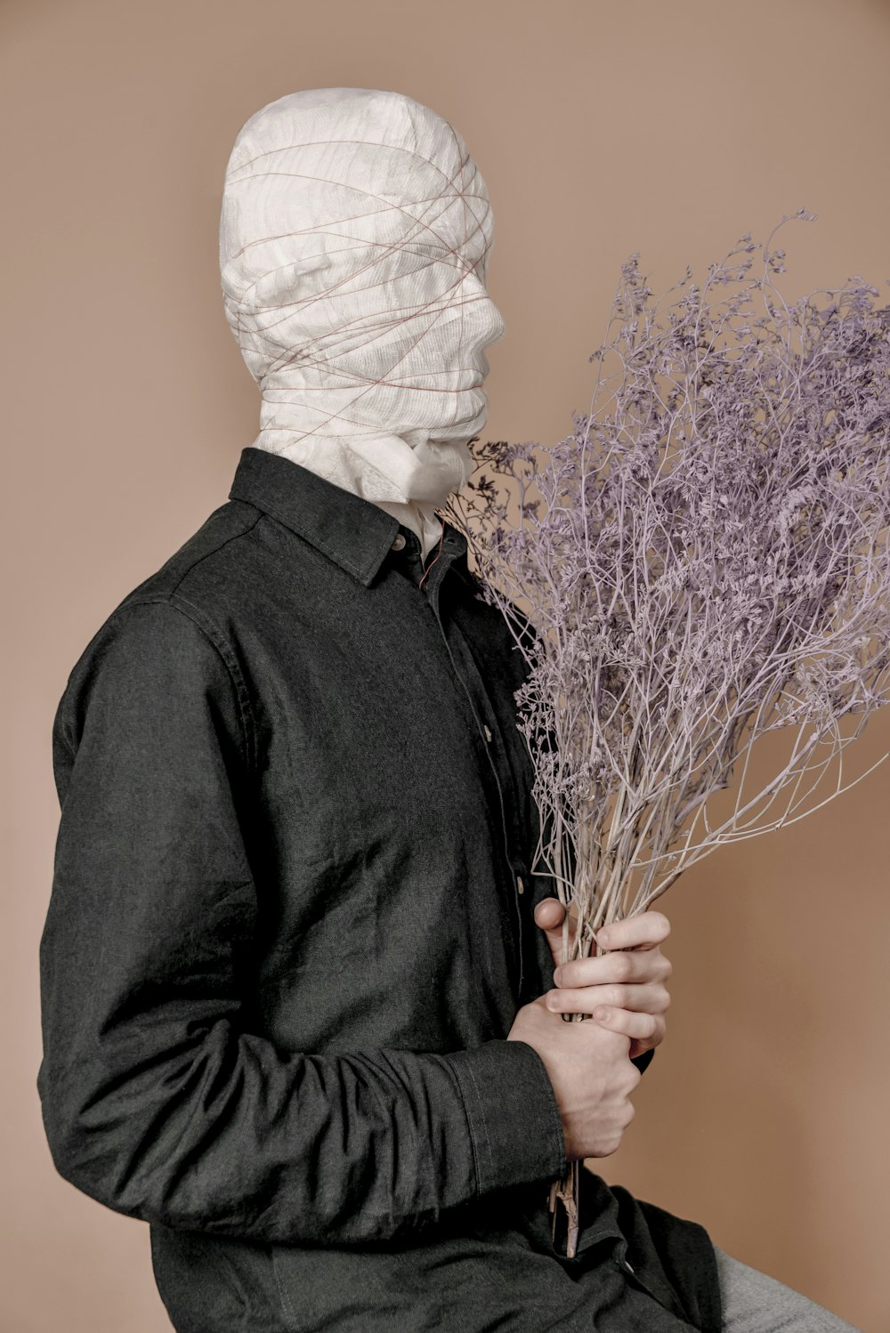 a man in a white mask holding a bunch of lavender