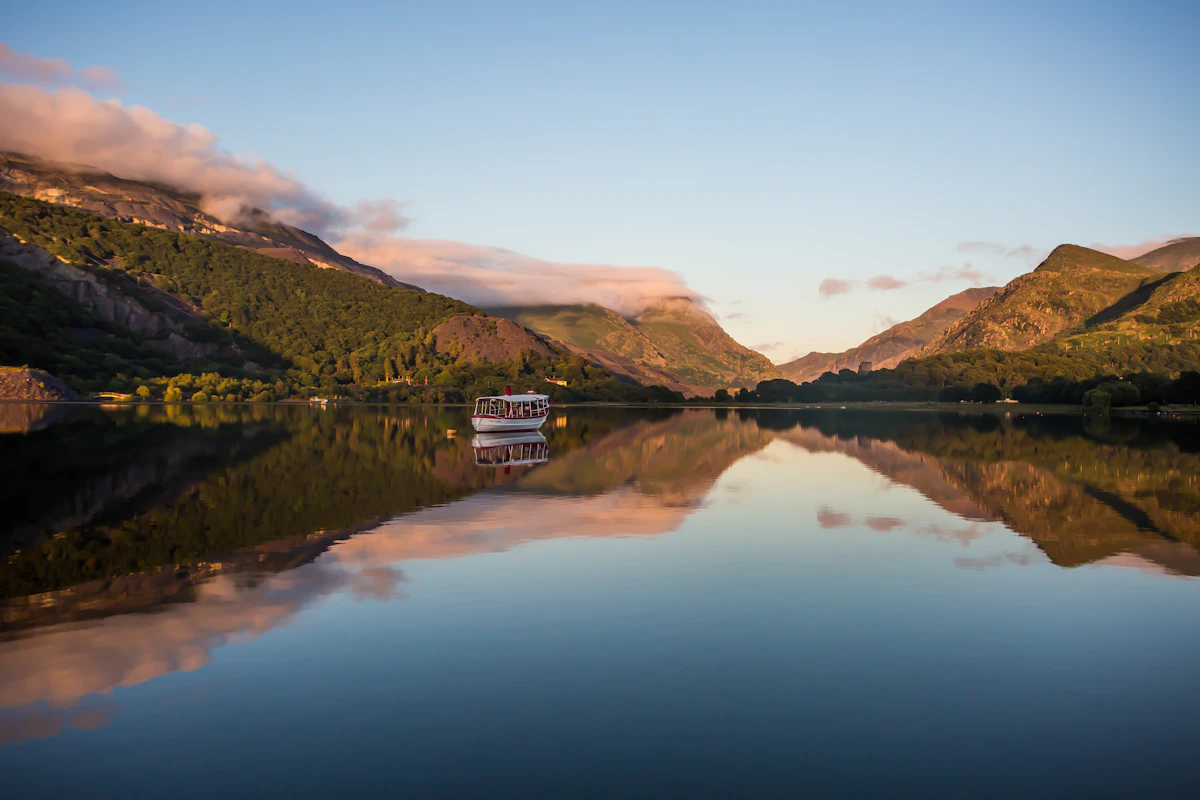 A small boat on a lake at Llanberis in low sun, with the hills mirrored in the water