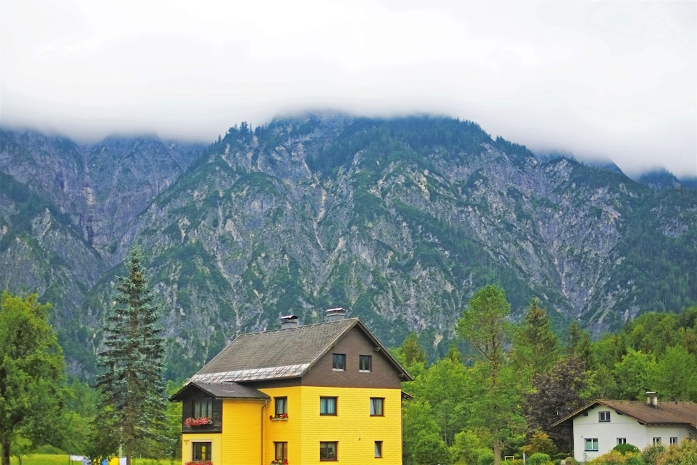 uma casa amarela com uma montanha no fundo