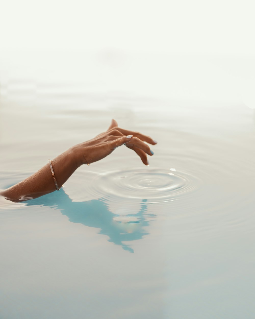 a person's hand reaching for something in the water