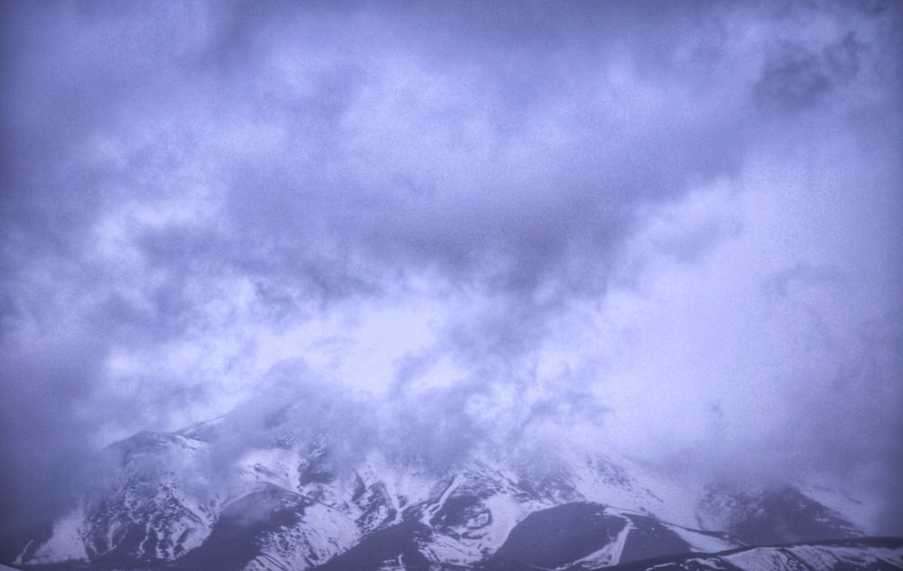 a snow covered mountain under a cloudy sky