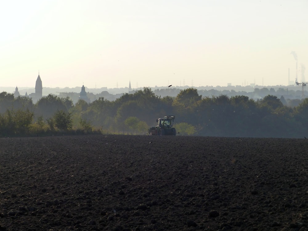 a tractor plowing a field with trees in the background