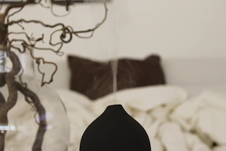 A peaceful bedroom scene with soft pillows, blackout curtains, and a diffuser emitting calming mist.