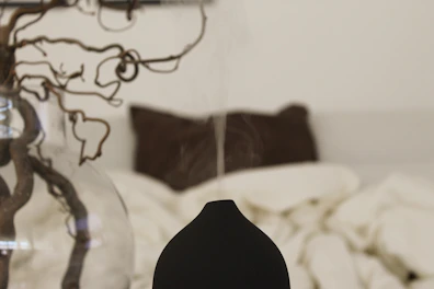 A peaceful bedroom scene with soft pillows, blackout curtains, and a diffuser emitting calming mist.