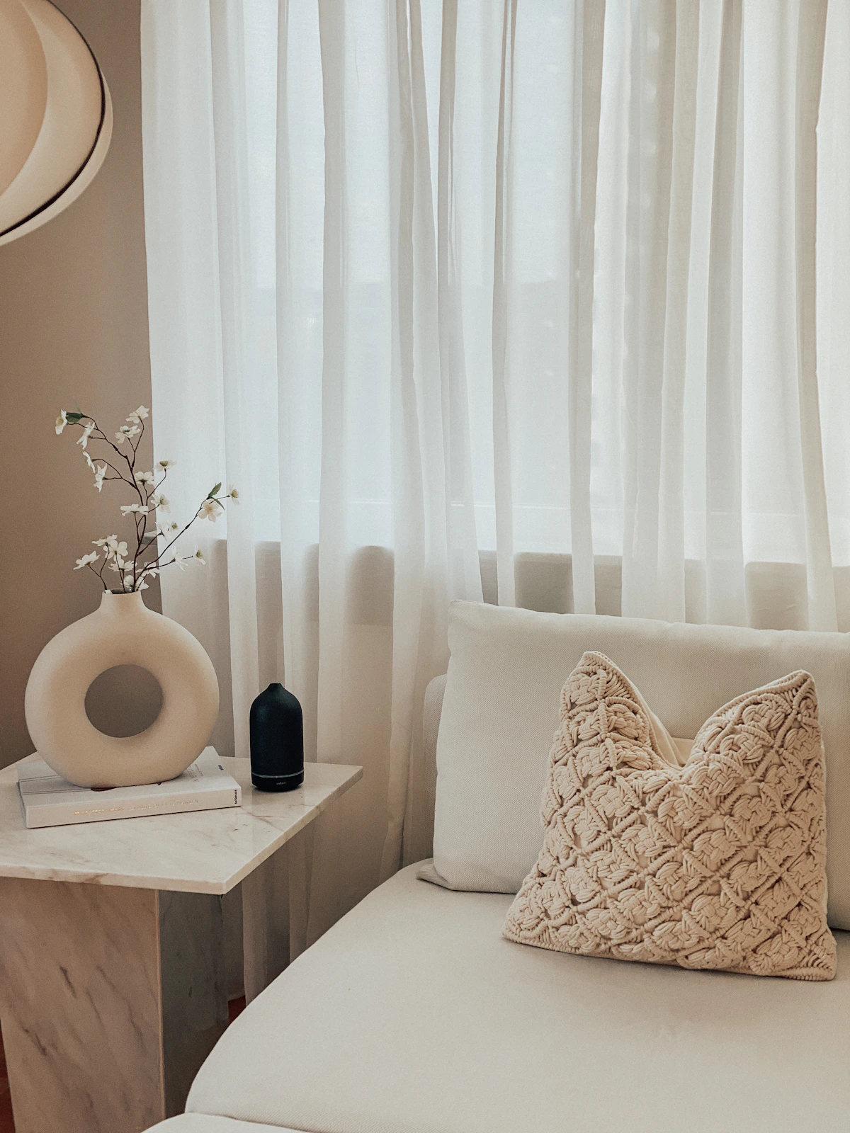 A bright living room with a white couch and white curtains