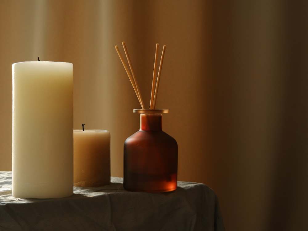 two candles and a bottle on a table
