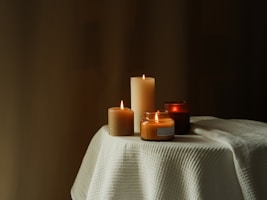 Close-up of colorful spell candles burning softly on a wooden table.