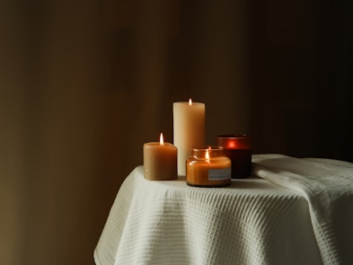 A cozy arrangement of glowing candles in various shapes and sizes on a wooden table.
