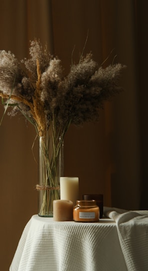 a vase with some flowers and candles on a table