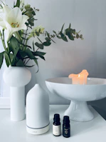 A serene morning scene with a moonlazy face serum beside a white ceramic vase and fresh flowers.