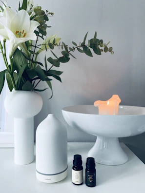 A serene morning scene with a moonlazy face serum beside a white ceramic vase and fresh flowers.