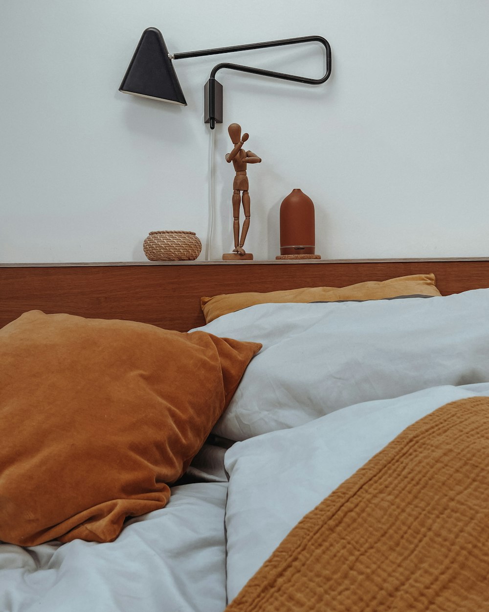 a bed with a wooden head board and a lamp on top of it