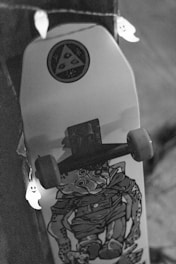 A skateboard with a graphic design featuring a stylized character. It is decorated with a string of small ghost lights, creating a playful and spooky atmosphere. The setting is dimly lit, focusing more on the skateboard and the lights.