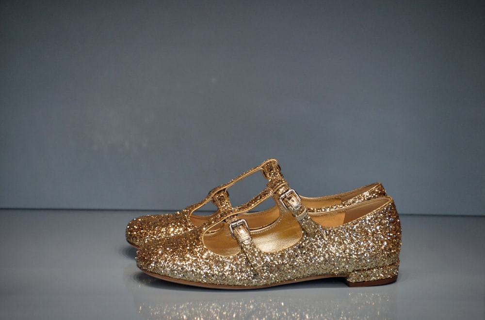 a pair of gold glitter shoes on a reflective surface