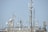 A variety of communication antennas and satellite dishes are mounted on a rooftop structure against a clear blue sky. The array includes different shapes and sizes of dishes, poles, and antennas, all made of metal and positioned at different heights.