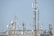 A variety of communication antennas and satellite dishes are mounted on a rooftop structure against a clear blue sky. The array includes different shapes and sizes of dishes, poles, and antennas, all made of metal and positioned at different heights.