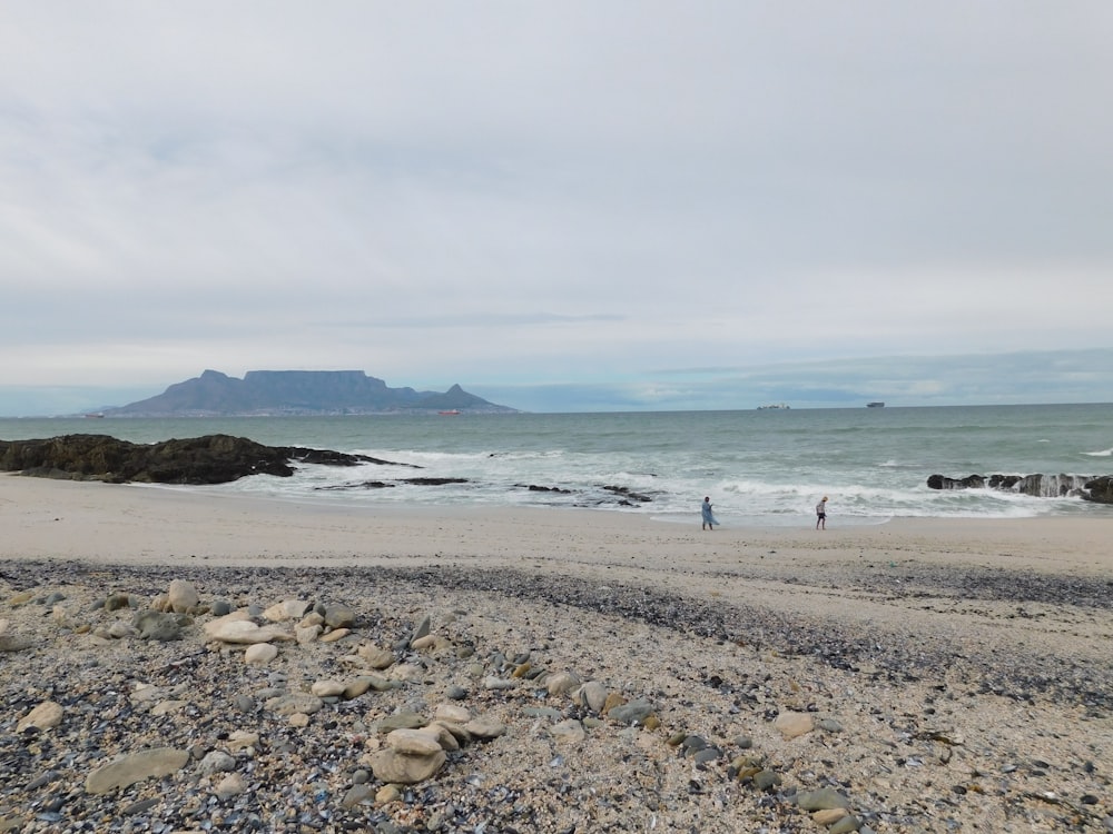 Un couple de personnes debout au sommet d’une plage de sable