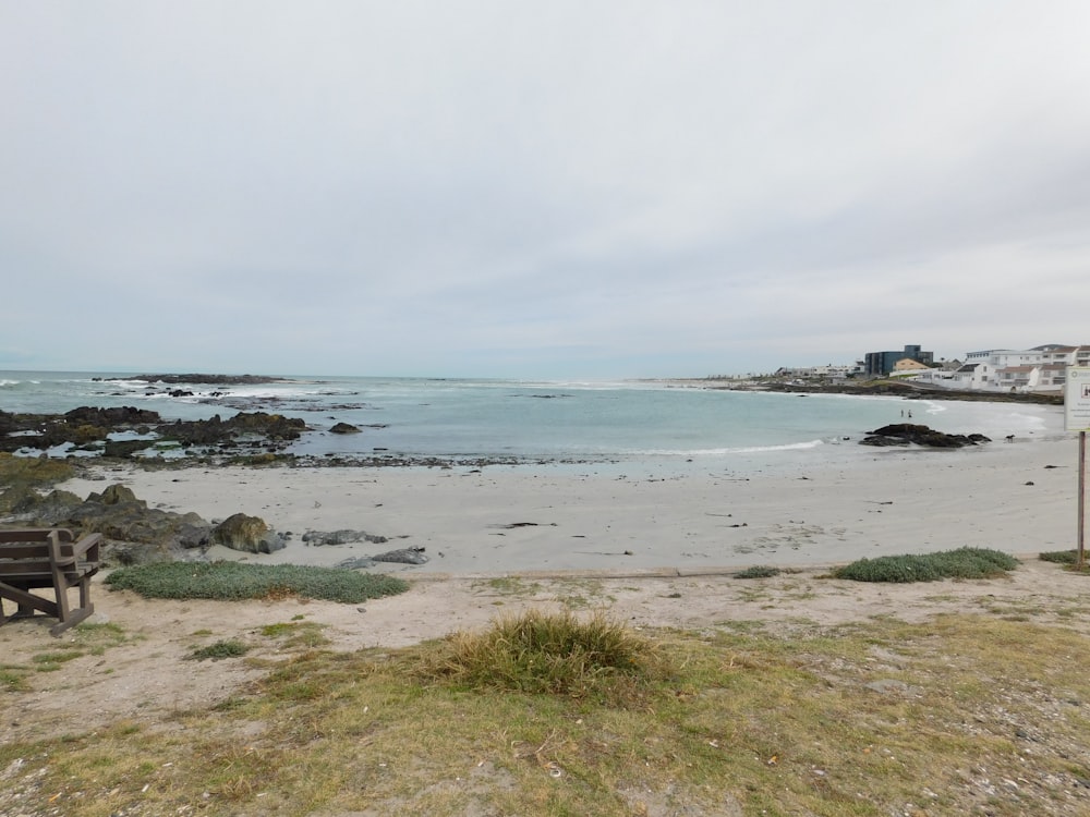 un banco de madera sentado en la parte superior de una playa de arena