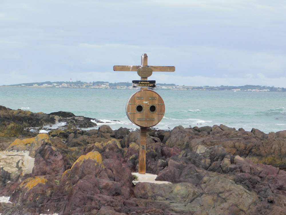 Un letrero de madera sentado en la cima de una playa rocosa