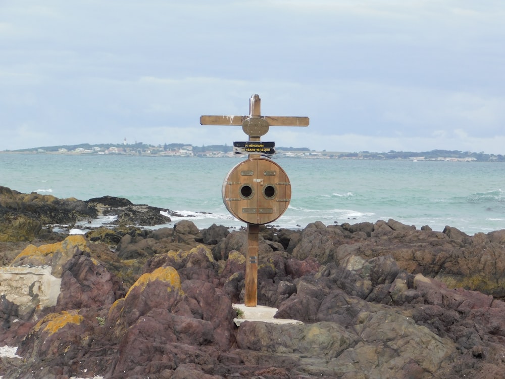 a wooden sign sitting on top of a rocky beach