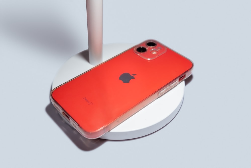 a red iphone sitting on top of a white stand