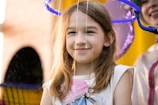 A close-up of a child blowing bubbles with a big smile on their face