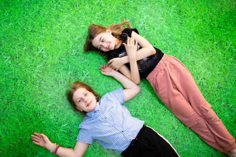 two young girls laying on the grass with their arms around each other