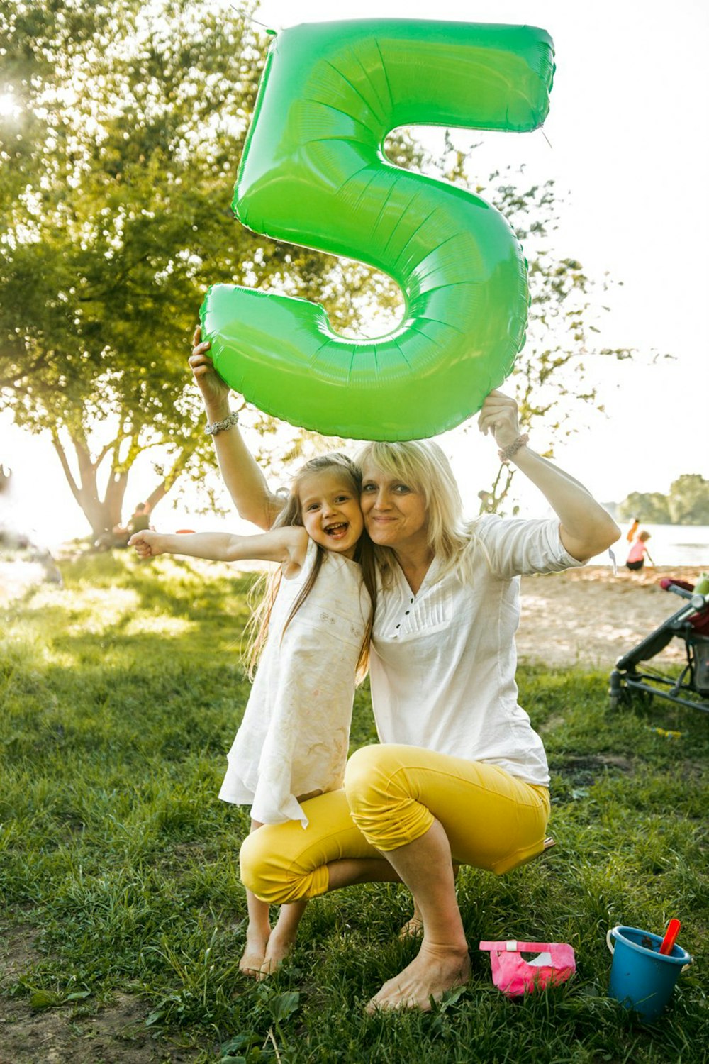 a woman and a little girl holding up a large green number