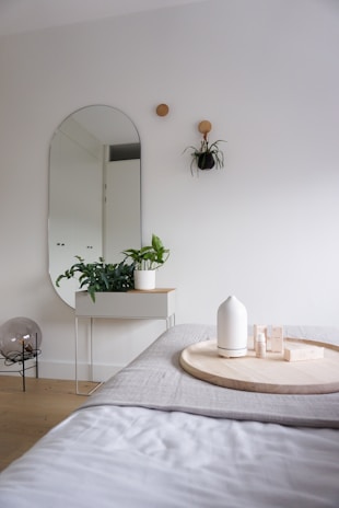 A full-length standing mirror placed beside a minimalist bedroom setup, highlighting its sleek design and functionality.