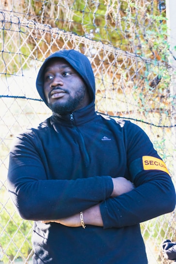 a man standing in front of a chain link fence agent de sécurité recrutement