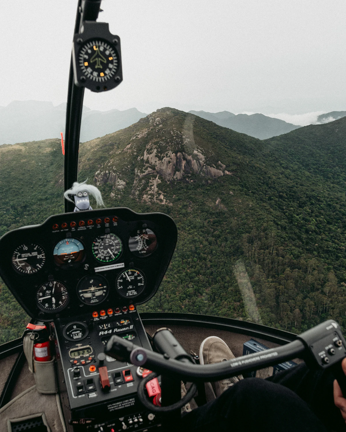 The view forward from inside a helicopter cockpit over a mountain range