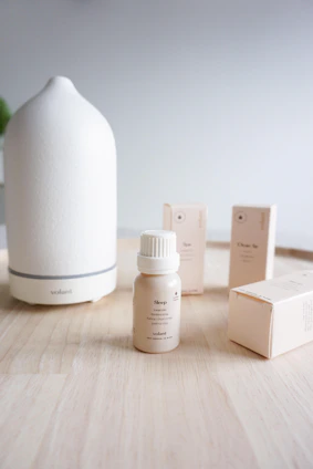 A serene display of natural essential oils and diffusers arranged on a wooden shelf with soft sunlight filtering through a window.